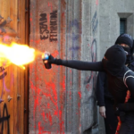 Normalistas de Ayotzinapa tumban puerta de Palacio Nacional para intentar entrar a hablar con AMLO